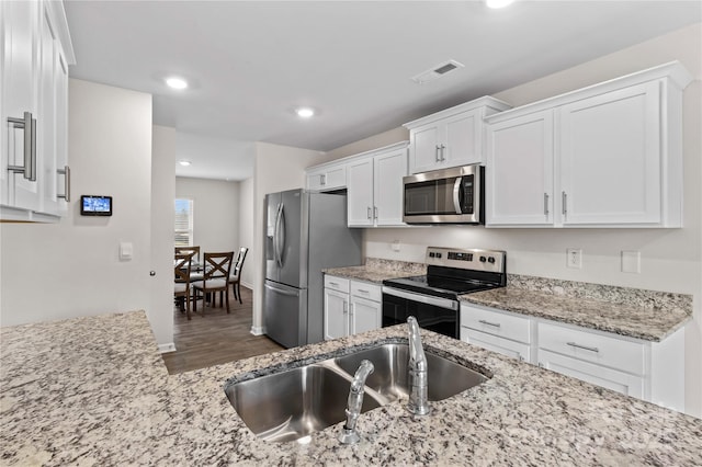 kitchen featuring sink, stainless steel appliances, dark hardwood / wood-style floors, light stone countertops, and white cabinets