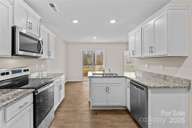 kitchen featuring sink, dark hardwood / wood-style flooring, kitchen peninsula, stainless steel appliances, and white cabinets