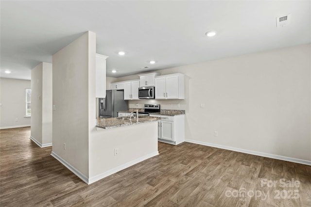 kitchen with stainless steel appliances, white cabinetry, light stone countertops, and dark hardwood / wood-style flooring