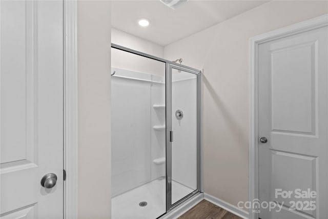 bathroom with hardwood / wood-style flooring and a shower with shower door