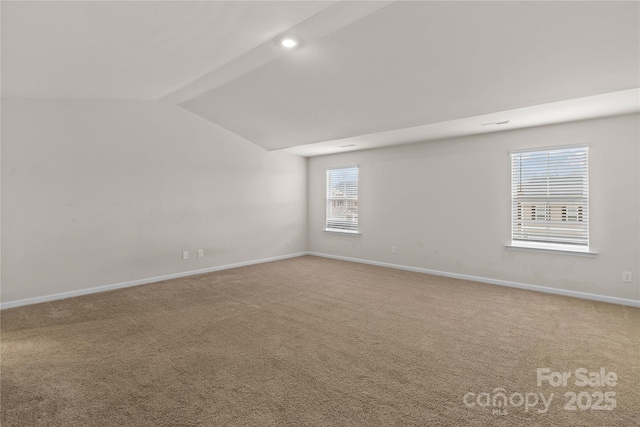 carpeted spare room featuring vaulted ceiling with beams