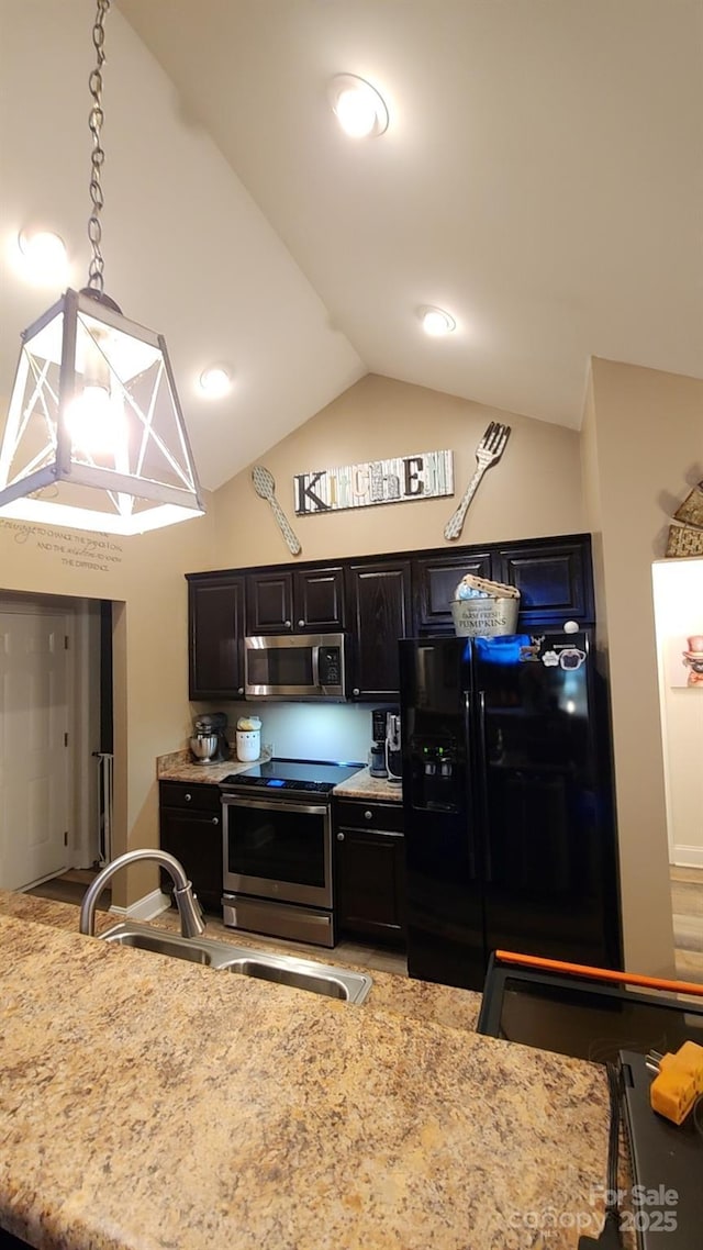 kitchen featuring vaulted ceiling, decorative light fixtures, sink, stainless steel appliances, and light stone countertops