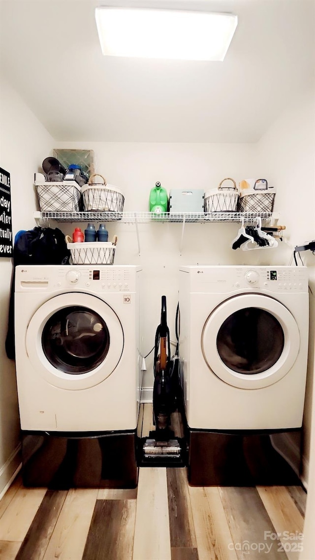 clothes washing area featuring separate washer and dryer and light hardwood / wood-style floors