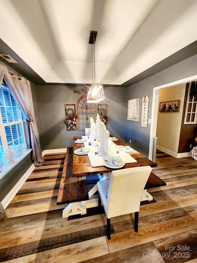 306 Bluegill Ln, Statesville, NC 28625 - dining room featuring visible vents, baseboards, a raised ceiling, and hardwood / wood-style flooring