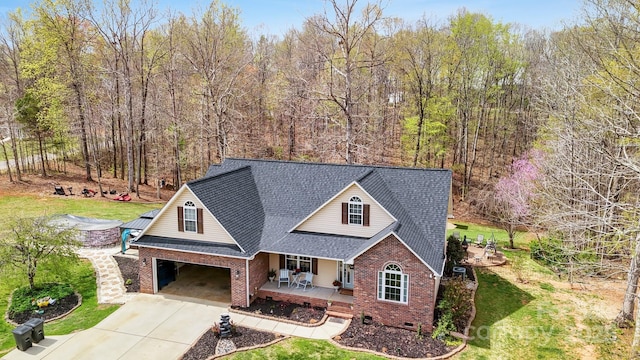 306 Bluegill Ln, Statesville, NC 28625 - view of front of house with a shingled roof, a porch, brick siding, a front lawn, and driveway