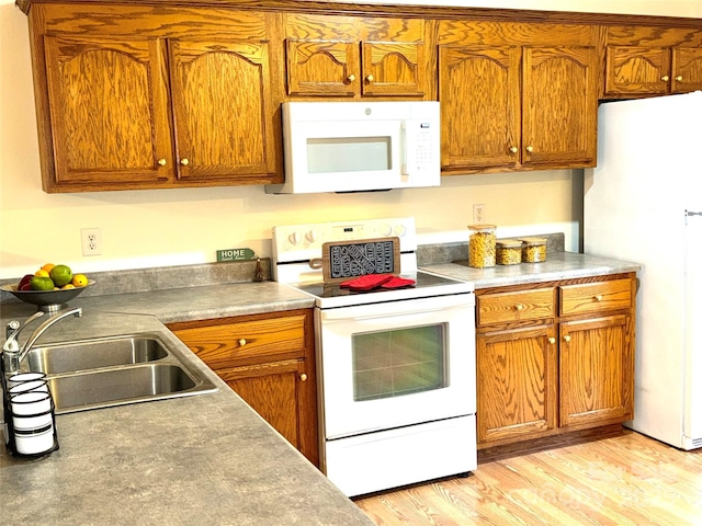 kitchen with sink, white appliances, and light hardwood / wood-style flooring