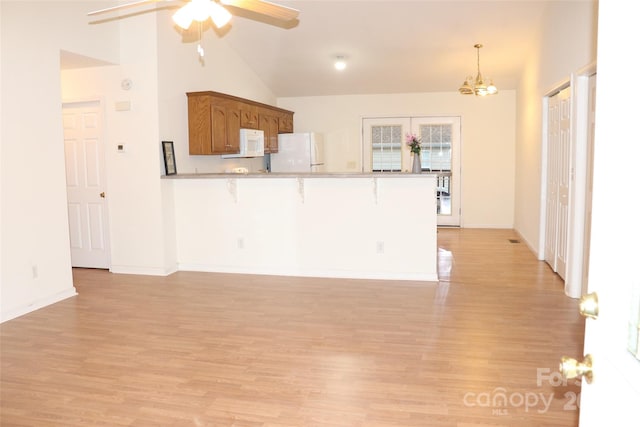 kitchen with a breakfast bar, decorative light fixtures, lofted ceiling, kitchen peninsula, and white appliances