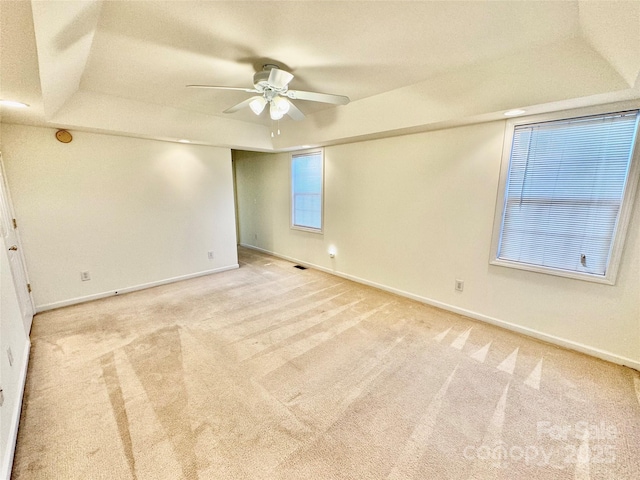 carpeted spare room with ceiling fan and a tray ceiling