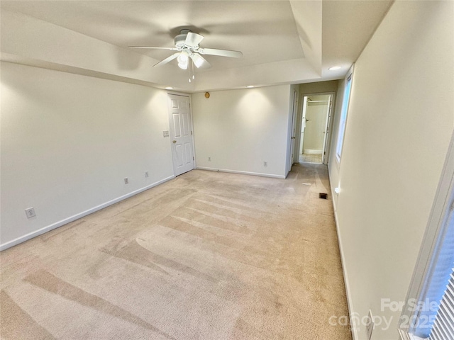 carpeted spare room featuring a tray ceiling and ceiling fan