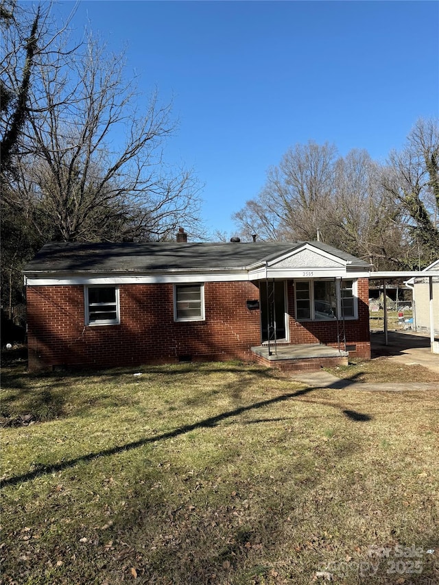 rear view of property with a lawn and a carport