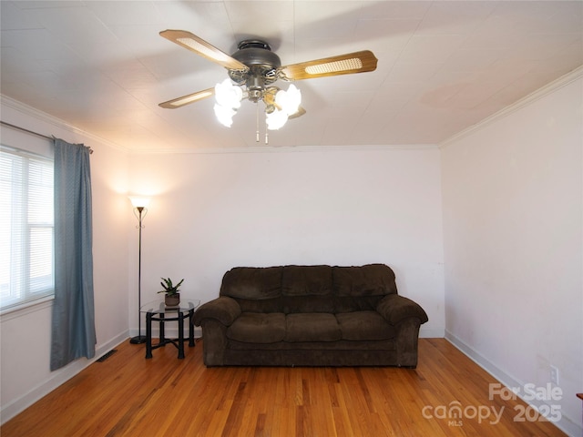 living area with hardwood / wood-style flooring, ornamental molding, and ceiling fan