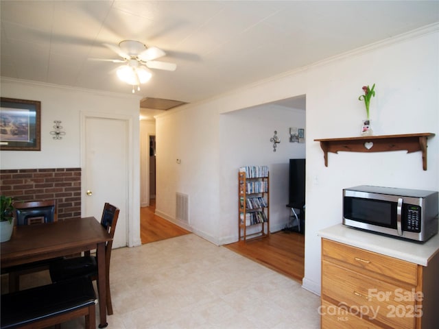 dining space with crown molding, a wood stove, and ceiling fan