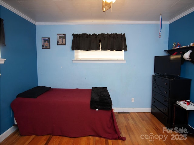 bedroom featuring crown molding and light hardwood / wood-style flooring