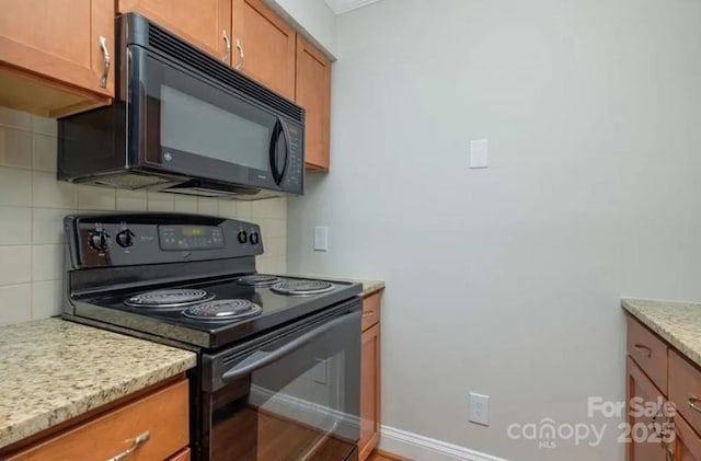 kitchen with light stone countertops, decorative backsplash, and black appliances