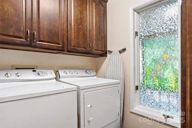 laundry room featuring cabinets, a wealth of natural light, and washing machine and clothes dryer