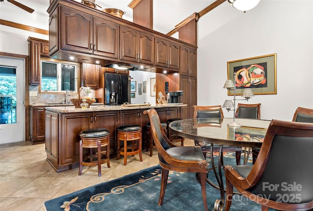 bar featuring sink, light tile patterned floors, tasteful backsplash, light stone countertops, and black fridge with ice dispenser