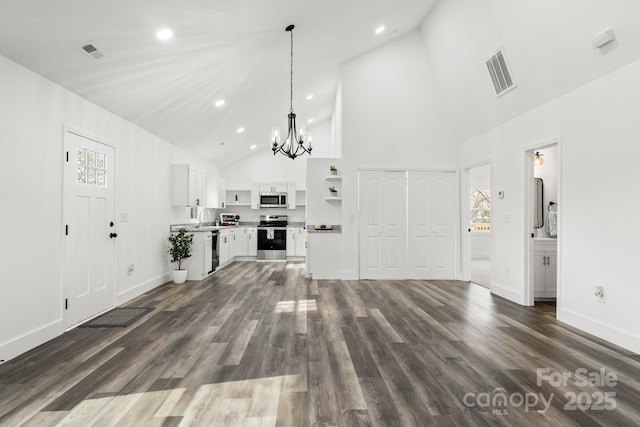 unfurnished living room featuring sink, dark hardwood / wood-style floors, a chandelier, and high vaulted ceiling