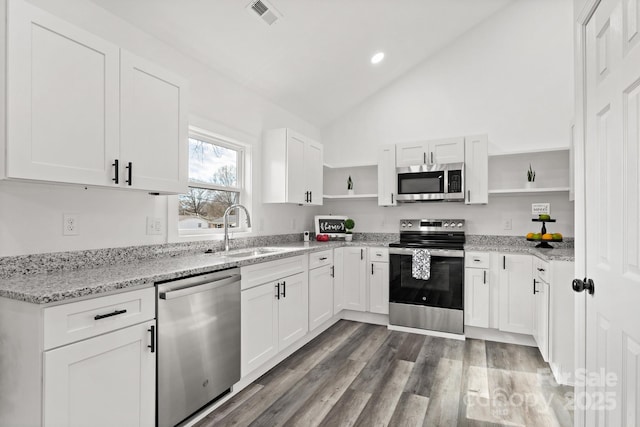 kitchen with hardwood / wood-style floors, sink, white cabinets, stainless steel appliances, and light stone countertops