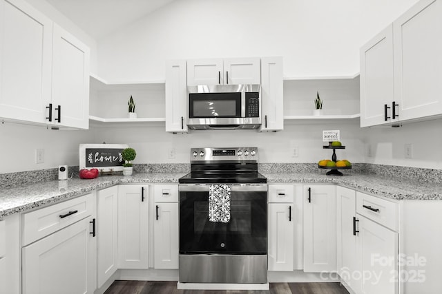 kitchen with stainless steel appliances, white cabinetry, light stone countertops, and dark hardwood / wood-style floors