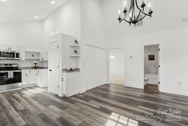 unfurnished living room with a towering ceiling, a chandelier, and dark hardwood / wood-style floors