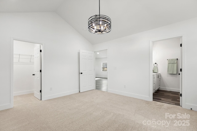 unfurnished bedroom featuring ensuite bath, high vaulted ceiling, light carpet, a spacious closet, and a closet