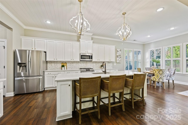 kitchen with sink, an inviting chandelier, hanging light fixtures, stainless steel appliances, and a kitchen island with sink