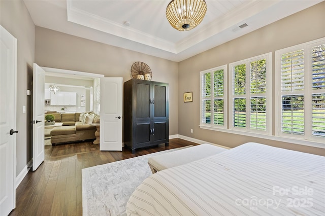 bedroom with dark hardwood / wood-style flooring, a raised ceiling, and an inviting chandelier