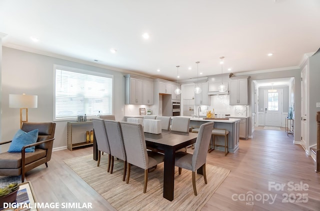 dining space featuring crown molding, sink, and light hardwood / wood-style flooring