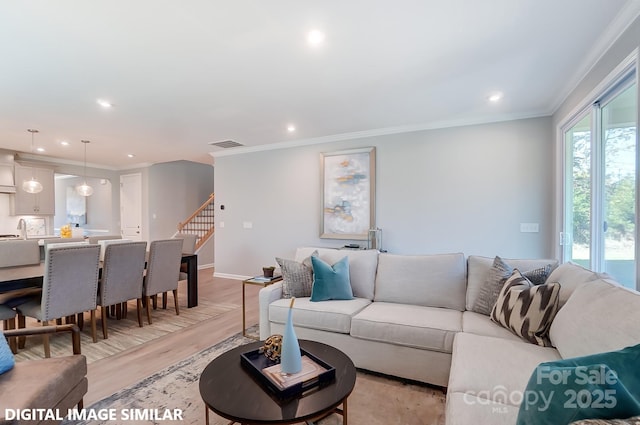 living room with crown molding, sink, and light hardwood / wood-style flooring