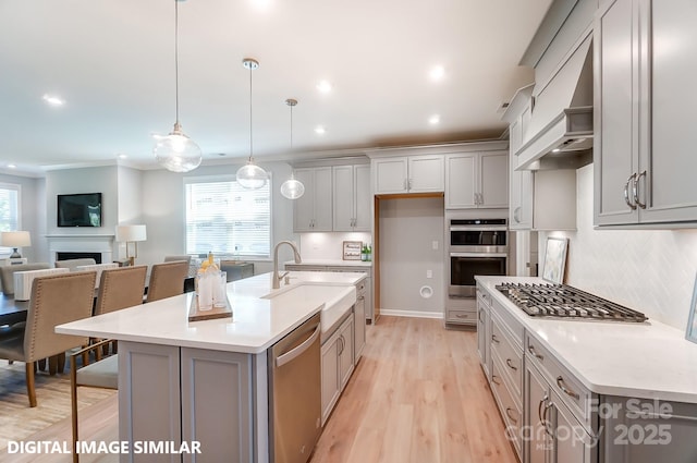 kitchen featuring a fireplace, appliances with stainless steel finishes, gray cabinets, and a sink