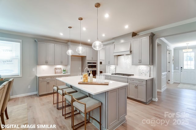 kitchen featuring gray cabinetry, stainless steel appliances, light countertops, ornamental molding, and custom range hood