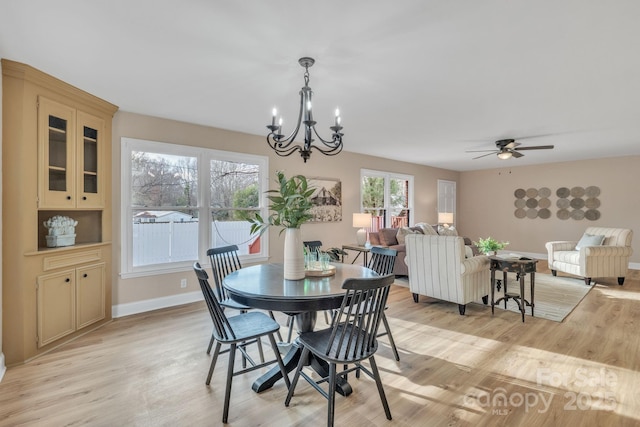 dining space with ceiling fan with notable chandelier and light wood-type flooring