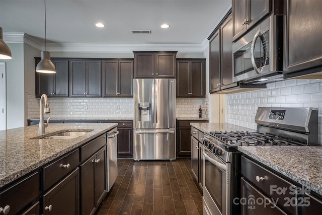 kitchen featuring appliances with stainless steel finishes, pendant lighting, sink, dark brown cabinetry, and light stone countertops