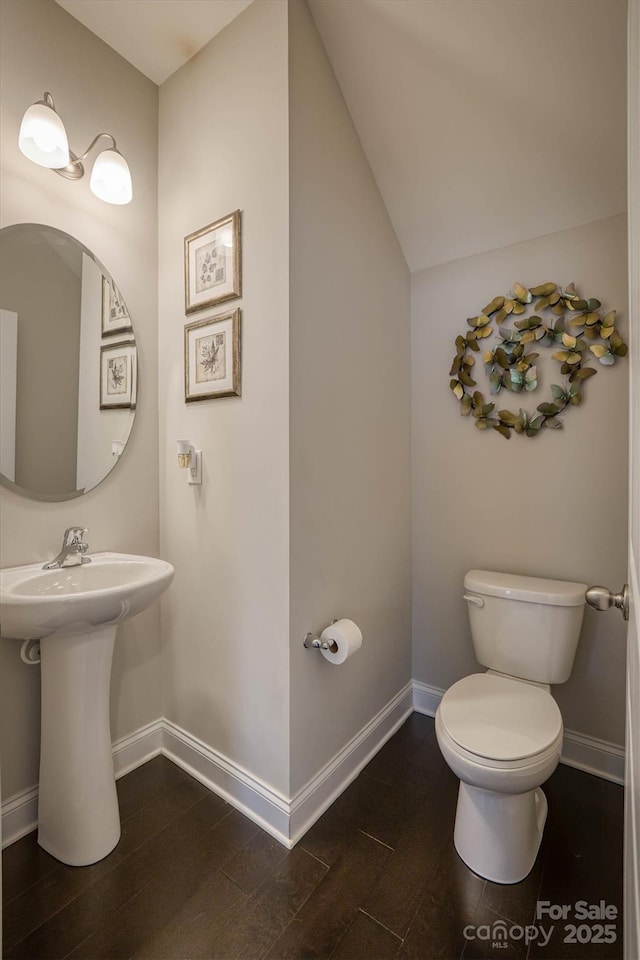 bathroom featuring lofted ceiling, hardwood / wood-style floors, sink, and toilet