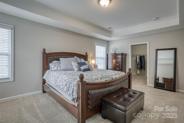 bedroom featuring light carpet, a tray ceiling, and multiple windows