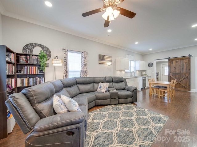 living room with ornamental molding, a barn door, and plenty of natural light