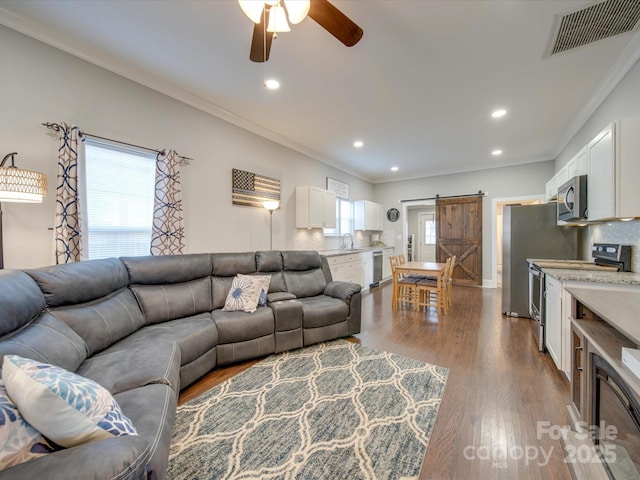 living room featuring crown molding, a barn door, a healthy amount of sunlight, and hardwood / wood-style floors