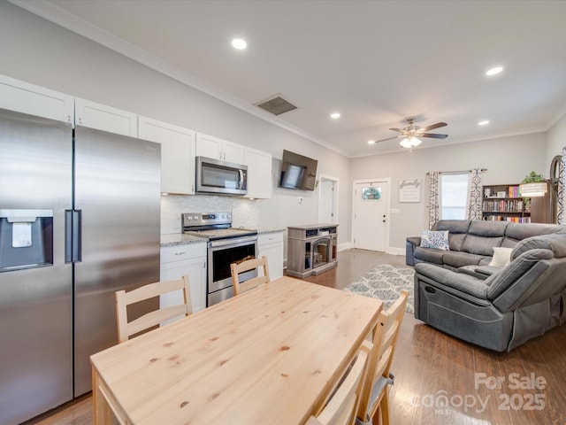 kitchen with stainless steel appliances, white cabinetry, tasteful backsplash, and dark hardwood / wood-style flooring