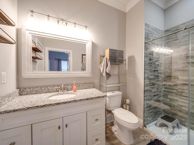 bathroom with crown molding, tiled shower, vanity, and toilet