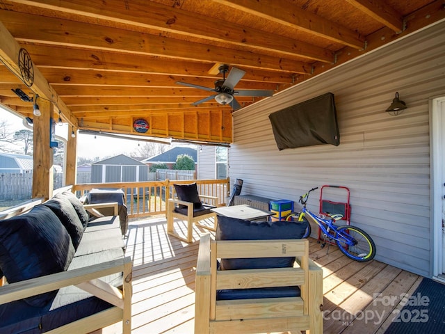 wooden deck featuring an outdoor living space, ceiling fan, and a storage shed