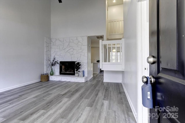 unfurnished living room featuring wood-type flooring and a stone fireplace