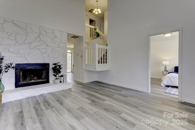 unfurnished living room featuring a towering ceiling, a fireplace, and light wood-type flooring