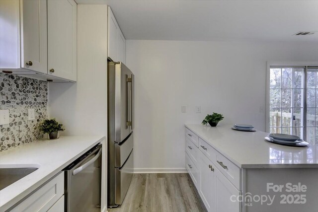 kitchen featuring decorative backsplash, light hardwood / wood-style flooring, white cabinets, and appliances with stainless steel finishes