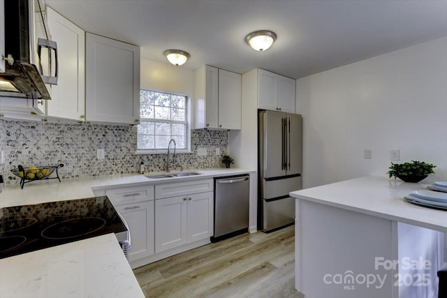 kitchen featuring sink, light hardwood / wood-style flooring, white cabinets, stainless steel appliances, and backsplash