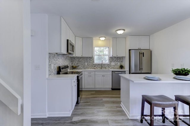 kitchen featuring sink, a breakfast bar, white cabinetry, stainless steel appliances, and kitchen peninsula