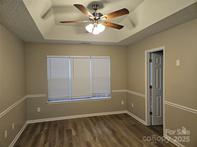 spare room with ceiling fan, a tray ceiling, dark hardwood / wood-style floors, and a textured ceiling