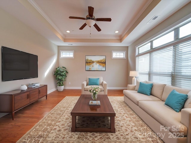 living room with crown molding, ceiling fan, a tray ceiling, and light hardwood / wood-style flooring