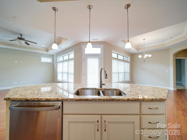 kitchen featuring light stone countertops, sink, stainless steel dishwasher, and a tray ceiling