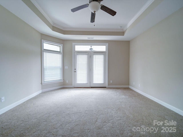 carpeted spare room with ceiling fan, ornamental molding, and a tray ceiling