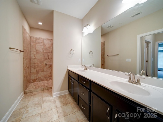 bathroom featuring tile patterned flooring, vanity, and a tile shower